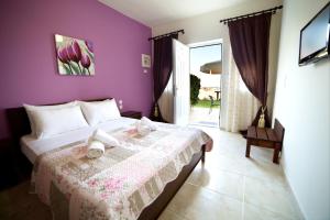 a purple bedroom with a bed with towels on it at GoldenHill Studios&apartments in Skiathos