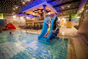 a woman riding a water slide in a swimming pool at Honey Paradise glamping resort in Dobova