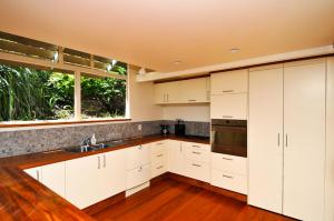 una cucina con armadi bianchi, lavandino e finestra di Beach Views Holiday Home a Nelson