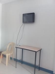 Elle comprend un bureau avec une chaise et une télévision murale. dans l'établissement D & B BLUESTAR BEACH RESORT, à Panglao
