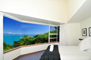 a bedroom with a large window with a view of the ocean at Beach Views Holiday Home in Nelson