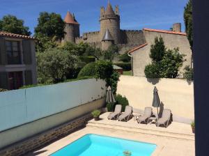 uma piscina com cadeiras e um castelo ao fundo em Hôtel l'Aragon em Carcassonne