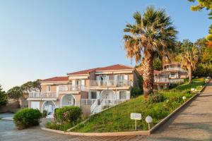 a large apartment building with palm trees on a hill at Iliovasilema in Platy