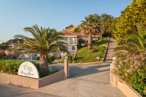 a walkway through a resort with palm trees and a sign at Iliovasilema in Platy
