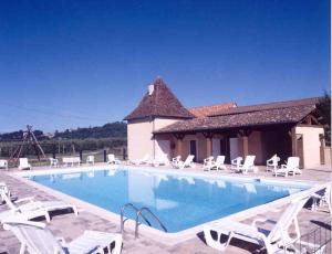 a large swimming pool with white chairs and a house at Domaine de La Vitrolle in Limeuil