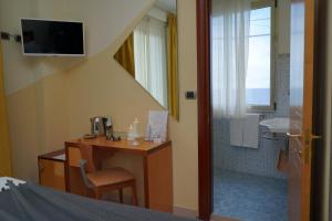 a bedroom with a desk and a bathroom with a shower at Piccadilly Rooms Restaurant and Beach in Santa Maria al Bagno