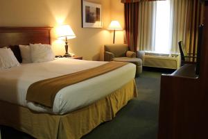 a hotel room with a large bed and a chair at Holiday Inn Express Tehachapi, an IHG Hotel in Tehachapi