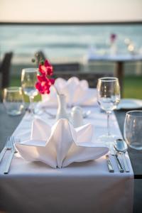 a table with white napkins and a red flower on it at Porto Platanias Beach Luxury Selection - Adults Only in Plataniás