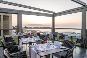 a restaurant with tables and chairs with a view of the ocean at Porto Platanias Beach Luxury Selection - Adults Only in Plataniás