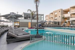 a swimming pool with chairs and umbrellas at a hotel at Porto Platanias Beach Luxury Selection - Adults Only in Plataniás