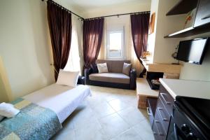 ein Schlafzimmer mit einem Bett und einem Sofa in einem Zimmer in der Unterkunft GoldenHill Studios&apartments in Skiathos-Stadt
