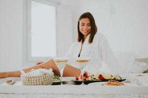 une femme assise à une table avec une assiette de nourriture dans l'établissement Myst Boutique Hotel, à Oia