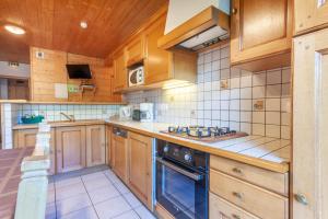 cocina con armarios de madera y horno con fogones en Clair Matin 2 en Morzine