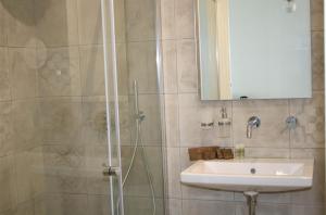 a bathroom with a shower, sink, and mirror at TOREMARE SUITE MARZAMEMI in Marzamemi