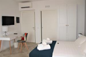 a room with a bed, chair and a television at TOREMARE SUITE MARZAMEMI in Marzamemi