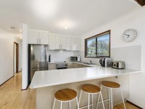 a kitchen with a white counter and stools in it at COASTAL BOHO VIBES FREE WIFI & NETFLIX - SURFSIDE in Inverloch