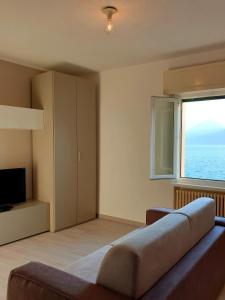 uma sala de estar com um sofá e uma grande janela em Assenza Lake Front Sweet Apartment em Brenzone sul Garda
