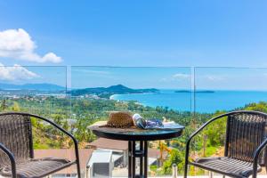 a table with a hat and two chairs on a balcony at Samui Villa Bebe in Bophut