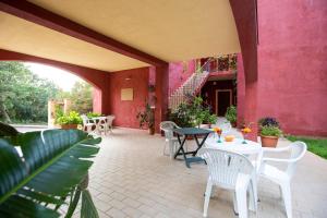 eine Terrasse mit Tischen und Stühlen und einer rosa Wand in der Unterkunft Albergo Residenziale Stella Dell'Est in Bari Sardo