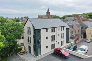 an apartment building with a red car parked in a parking lot at Apt 1, Frasers Close, Kirkwall in Kirkwall