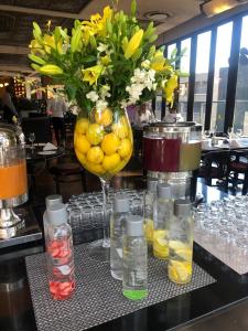 einen Tisch mit einer Vase aus Blumen und Getränken in der Unterkunft DAVINCI Hotel on Nelson Mandela Square in Johannesburg