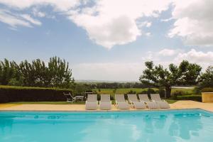 eine Gruppe von Stühlen neben einem Pool in der Unterkunft Gîte du Domaine de Coutancie in Prigonrieux