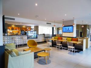 un restaurante con bar y algunas sillas y mesas en Campanile Val de France, en Magny-le-Hongre