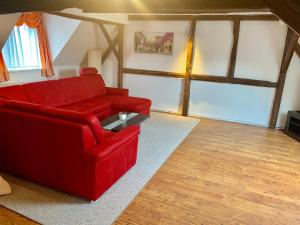 un soggiorno con divano rosso e tavolo di Ferienwohnungen Grimma 3 a Grimma