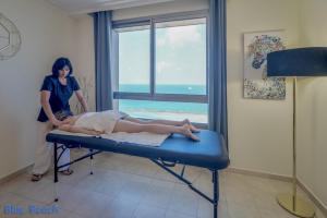a woman is laying on a bed in a room at מגדל אלמוג חיפה - דירות "בלו ביץ'" על הים in Haifa