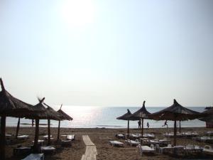 a beach with chairs and umbrellas and the ocean at Studio Olimp Black Sea in Olimp