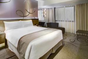 高雄市にある高雄 シャトー ド シン ホテルの白い大型ベッドと椅子が備わるホテルルームです。