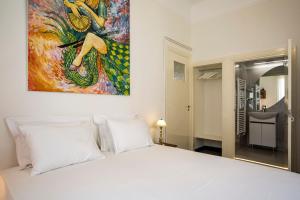 ein Schlafzimmer mit einem weißen Bett und einem Gemälde an der Wand in der Unterkunft Delightful 2 bedr'm 2 bathr'm apt with green roof top! - EP9U in Athen