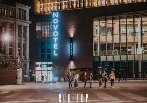 eine Gruppe von Menschen, die vor einem Gebäude spazieren gehen in der Unterkunft Novotel Charleroi Centre in Charleroi