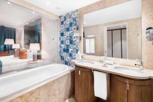 a bathroom with a tub and a sink and a large mirror at Cascade Wellness Resort in Lagos