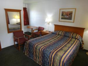 a hotel room with a bed and a table and a mirror at Tower Motel in Green Bay