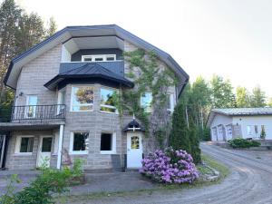 uma casa de tijolos com varanda e flores roxas em Villa Ateljeerinne em Vaajakoski