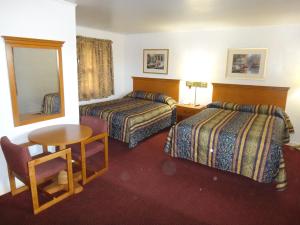 a hotel room with two beds and a table and a mirror at Tower Motel in Green Bay