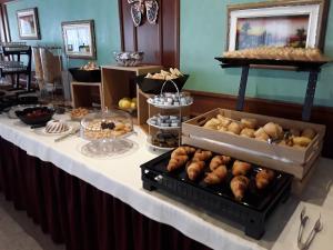 un buffet de bollería y otros alimentos en una mesa en Hotel Bellaria, en Levico Terme