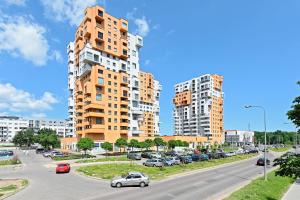 ulica z samochodami zaparkowanymi przed wysokimi budynkami w obiekcie Comfort Apartments Horyzonty w Gdańsku