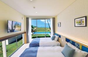 宮古島にあるフェリスヴィラスイート伊良部島・佐和田の大きな窓付きの客室で、ベッド2台が備わります。
