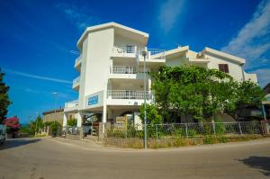 a white building with a tree in front of it at Apartmani Vitic in Bar