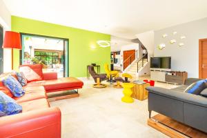 a living room filled with furniture and a tv at La Musarde, magnifique villa avec piscine chauffée à deux pas de la plage de Boucan Canot in Saint-Gilles les Bains