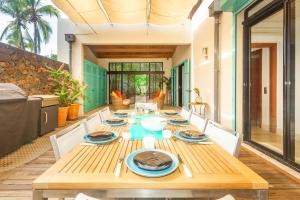 a dining room with a wooden table and chairs at La Musarde, magnifique villa avec piscine chauffée à deux pas de la plage de Boucan Canot in Saint-Gilles les Bains