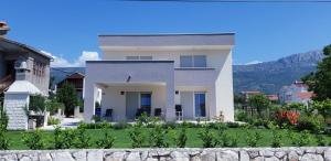 a large white house with a garden in front of it at Navi in Kaštela