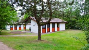 un edificio con pareti bianche e arancioni e un albero di Ferienpark Grafschaft Bentheim a Uelsen