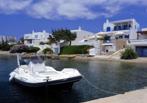 a white boat on the water in front of houses at Heliotropio Studios & Apartments in Pollonia
