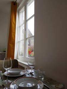 una mesa con platos y vasos en una mesa con ventana en l'Otis et le Titouan Saint-Sauveur, en Dinan