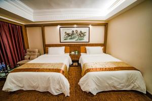 um quarto de hotel com duas camas e uma cadeira em Nanyang King's Gate Hotel em Guangzhou