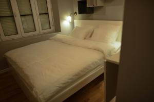 łóżko z białą pościelą i poduszkami w pokoju w obiekcie MAGIC GARDEN ZAGREB CENTER w Zagrzebiu
