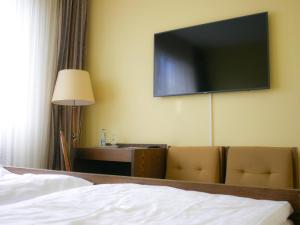 a hotel room with a bed and a television on the wall at Hotel Oronto in Koblenz